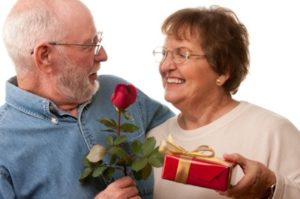 Happy Senior Couple with Gift and Red Rose Isolated on a White Background.